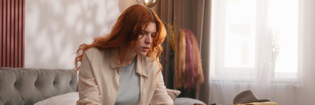 Schmuckbild: Frau, die gestresst auf Laptopbildschirm schaut und Reisepass und Flugtickets in der Hand hält.