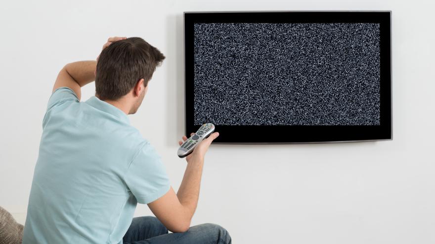 Mann sitzt vor defektem Fernsehgerät