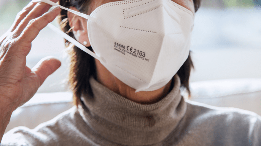 Eine Frau zieht sich eine FFP2-Maske auf.