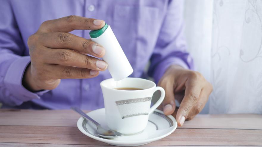 Ein Mann süßt Kaffee mit Süßstoff.