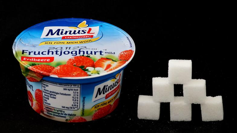 Joghurtbecher von Minus L und daneben eine Zuckerwürfel-Pyramide