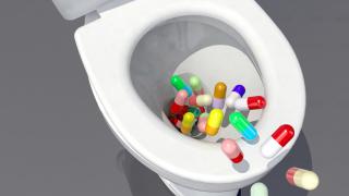 Tabletten fallen in eine Toilette