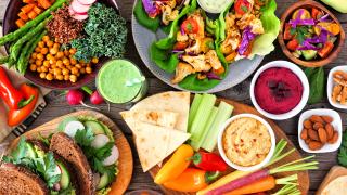 Ein Tisch voll mit veganen und vegetarischen Lebensmitteln: Früchte, Brot, Obst, Salat