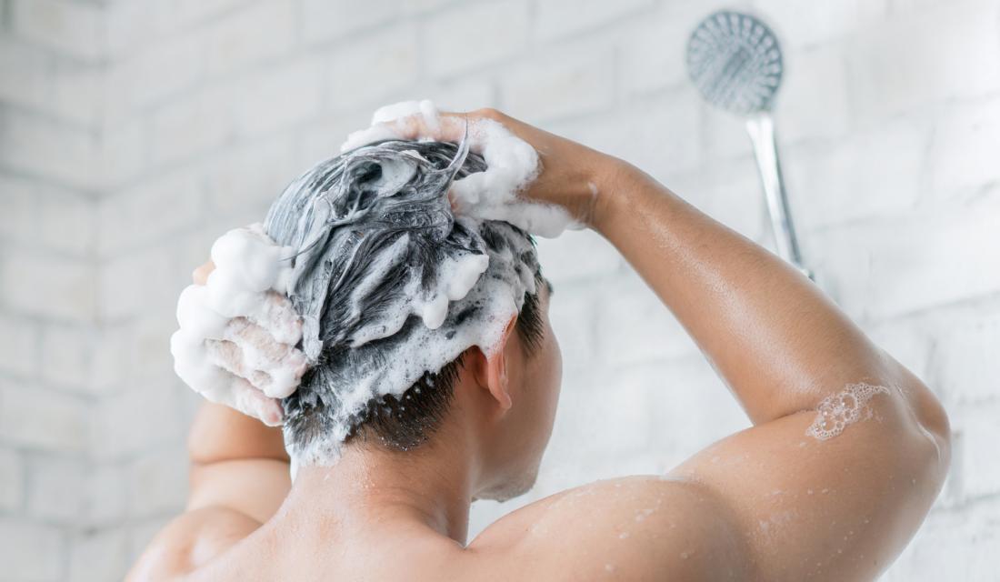 Ein Mann wäscht sich unter der Dusche die Haare