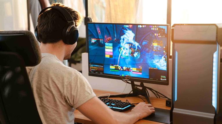 Ein Junge spiel ein Online-Game und hat Headphones auf.